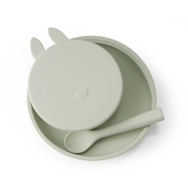 Sage green children's bowl, spoon, and lid set on a white background