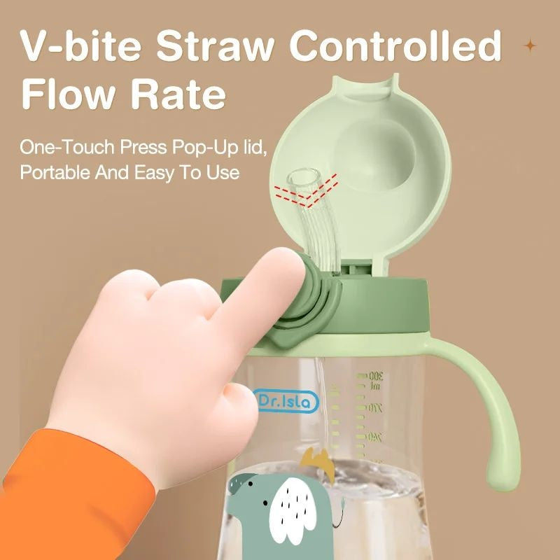 Green sippy cup with V-bite straw and pop-up lid, held by a hand against a beige background.