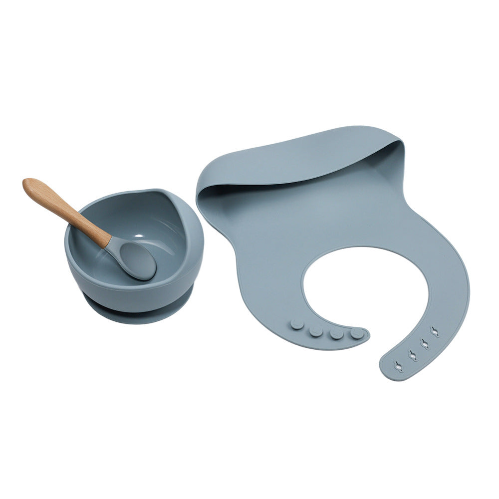 Gray baby bowl with wooden spoon and bib on a white background