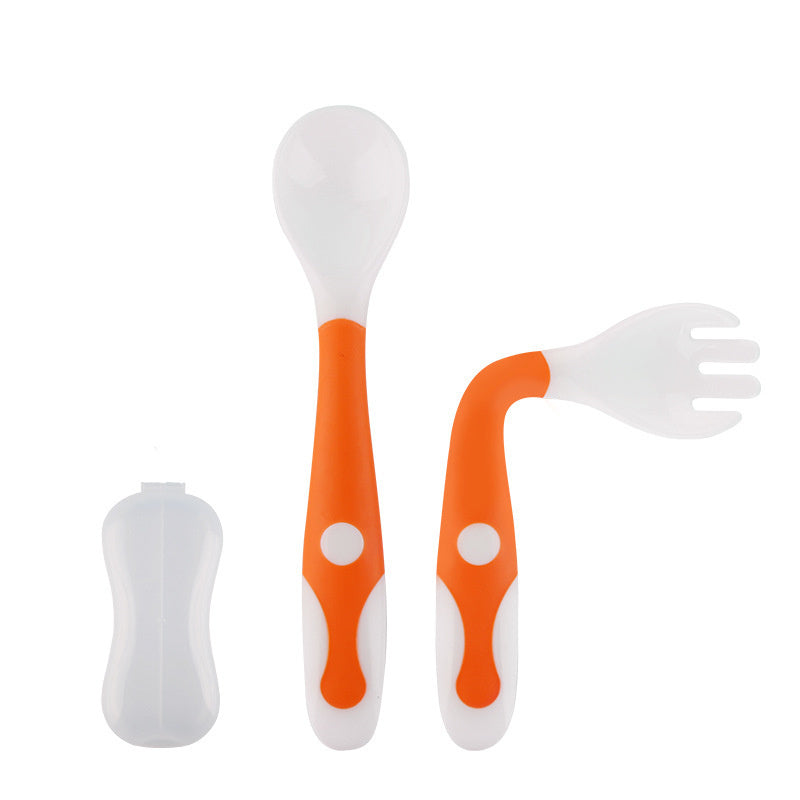 Set of orange and white baby utensils including a spoon, fork, and straw on a white background