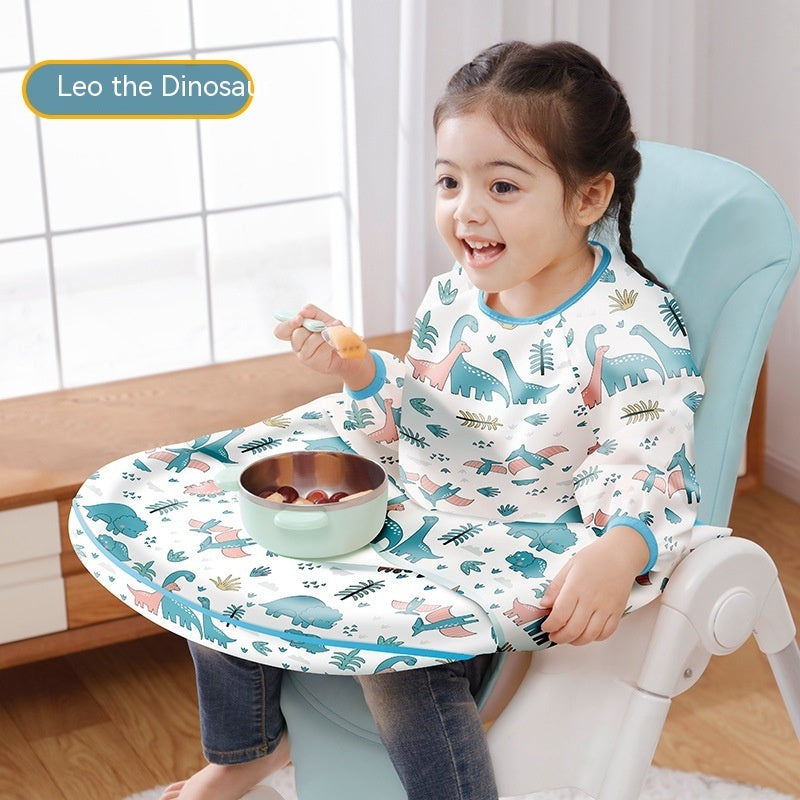 Child sitting in a booster seat with a dinosaur-themed tray and bib, smiling.