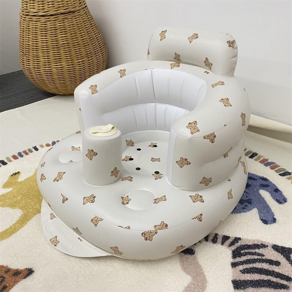 White inflatable baby seat with teddy bear patterns on a patterned rug.