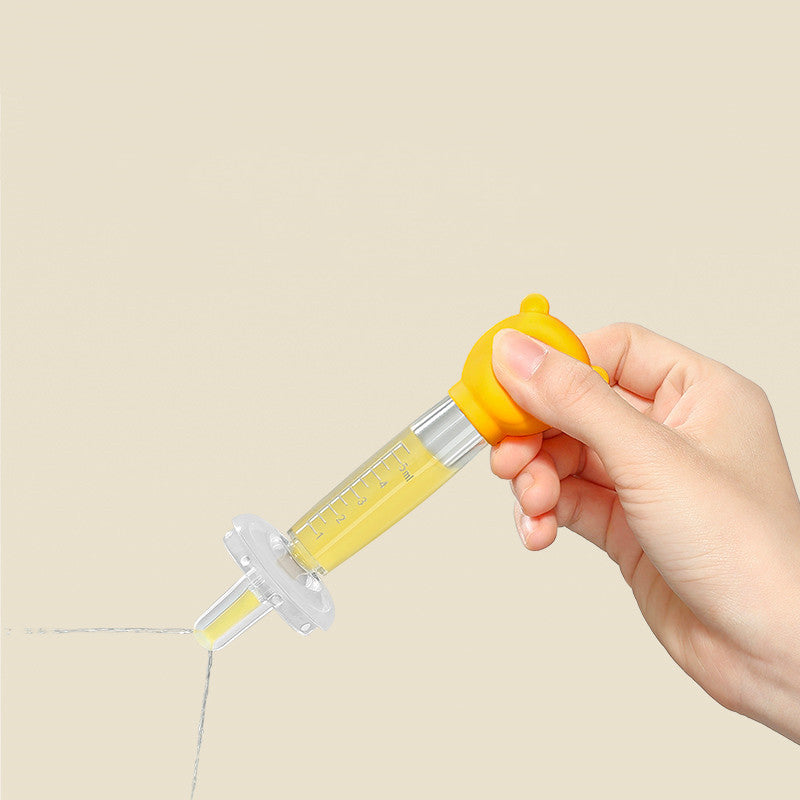 Hand holding a yellow syringe with a clear liquid on a beige background