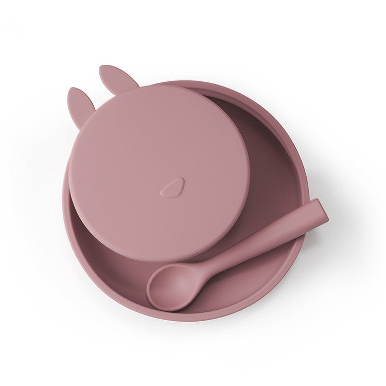 Pink silicone bowl with lid and spoon on a white background