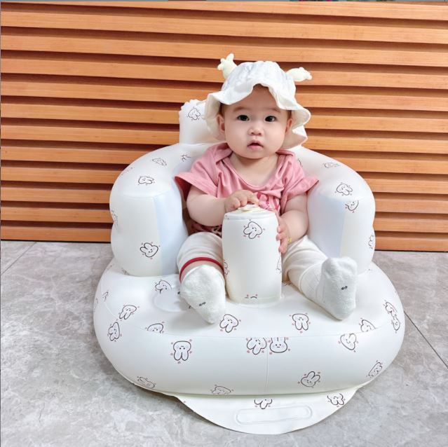 Baby sitting on a white inflatable chair with animal patterns against a wooden background