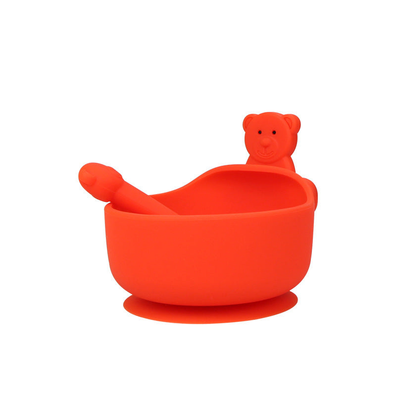 Orange silicone baby bowl with spoon and bear-shaped cover on a white background