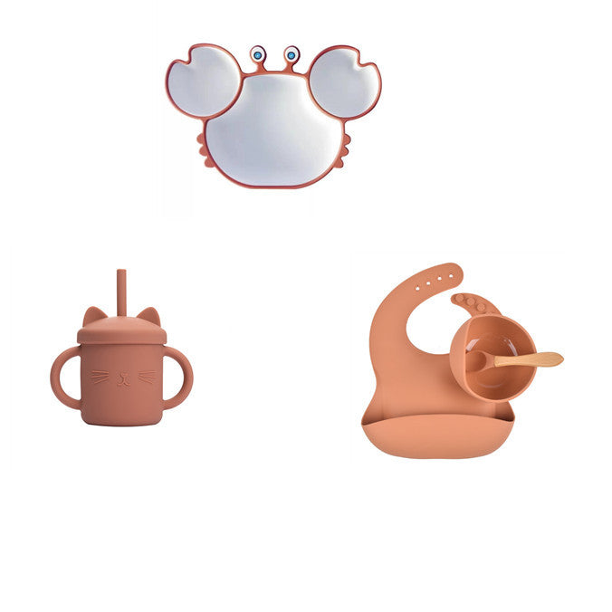 Set of children's tableware including a cup, sippy cup, and bib with a mirror on a white background.