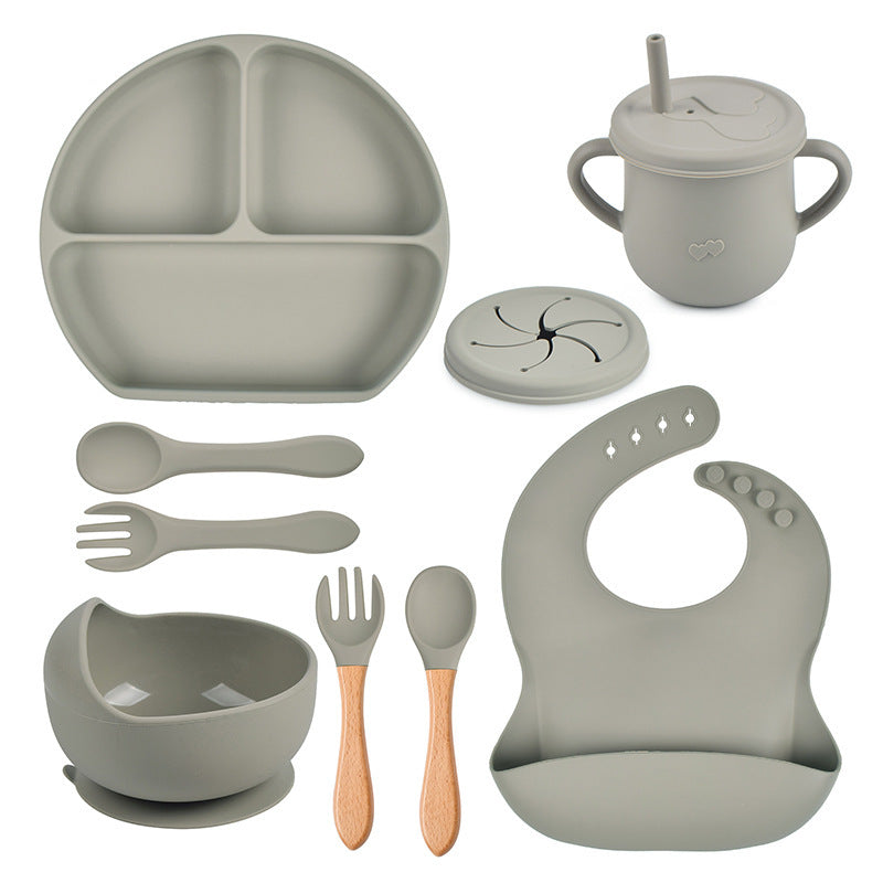 Children's dining set with plate, cup, bowl, utensils, and bib on a white background