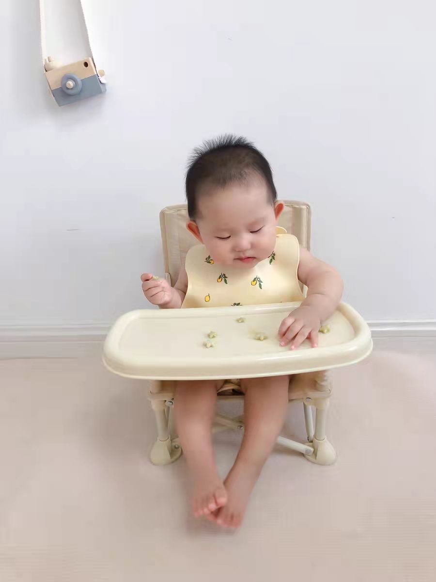 Baby sitting in a high chair with a white background