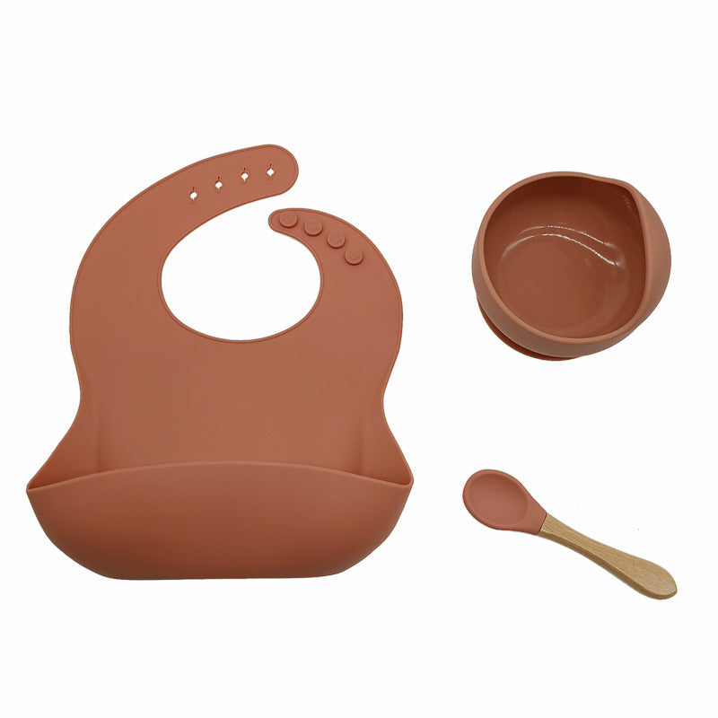 Brown silicone bib, bowl, and spoon set on a white background