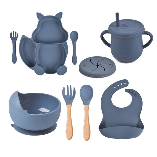 Blue silicone dining set with bowl, cup, spoon, fork, and bib on a white background