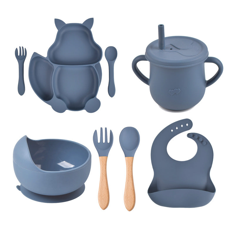Blue silicone dining set with bowl, cup, spoon, fork, and bib on a white background