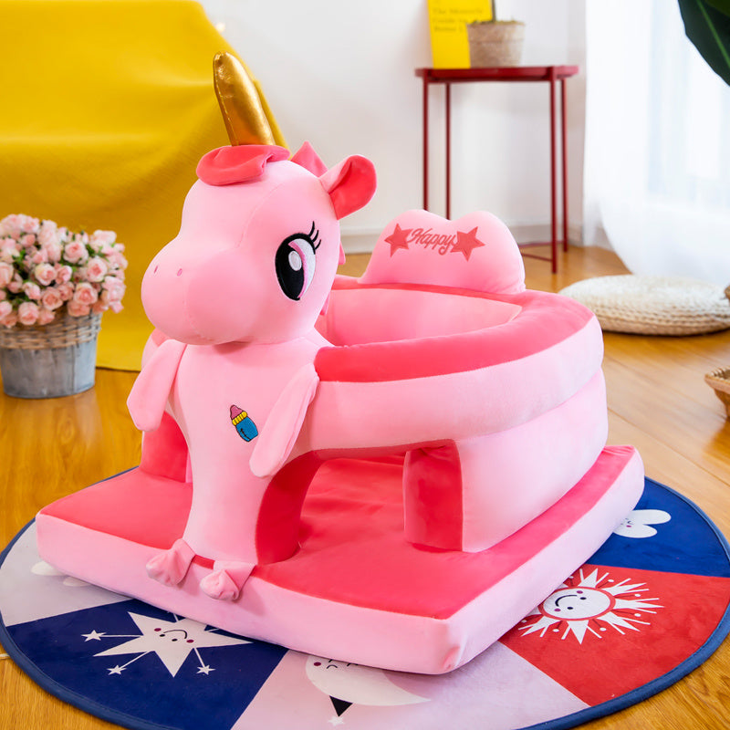 Pink unicorn toy with a gold horn on a wooden floor.
