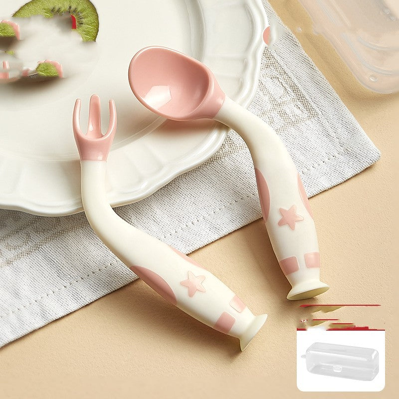 Children's pink and white utensils on a beige surface with a plate and napkin in the background.