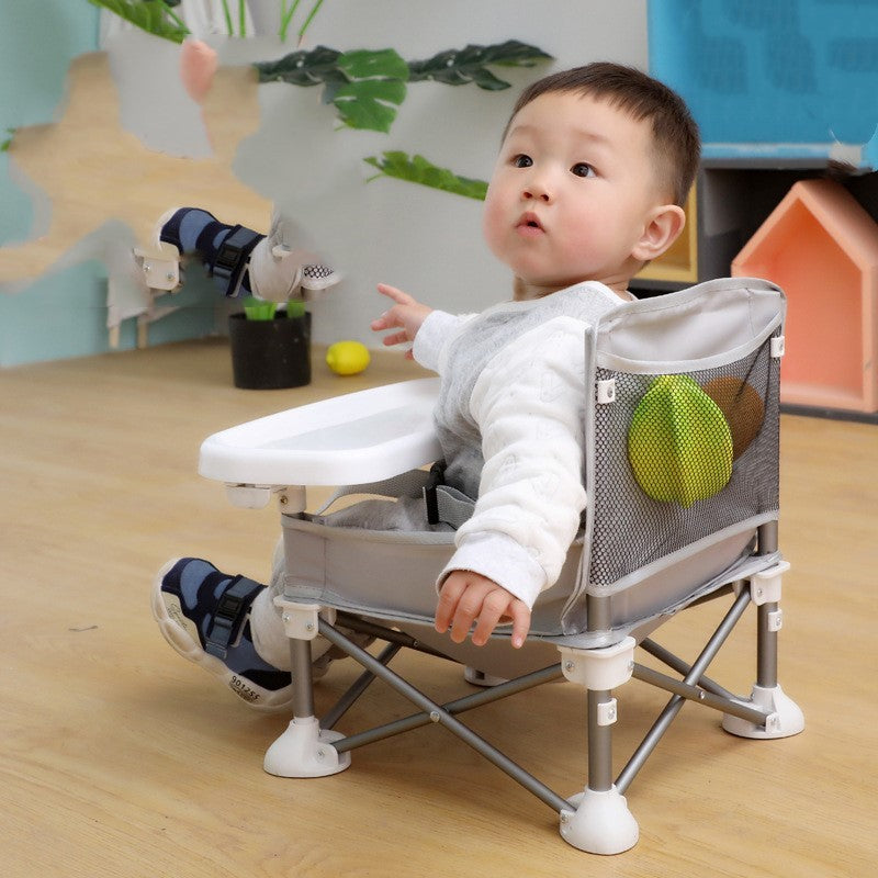 Child sitting in a small folding chair with a toy in a room with toys and furniture.