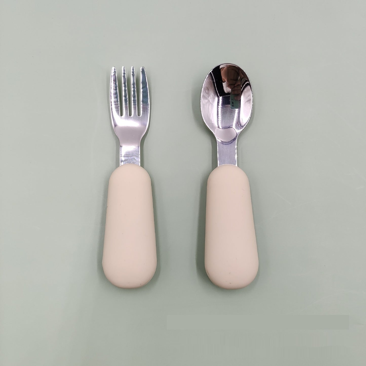 Fork and spoon set with beige handles on a light gray background