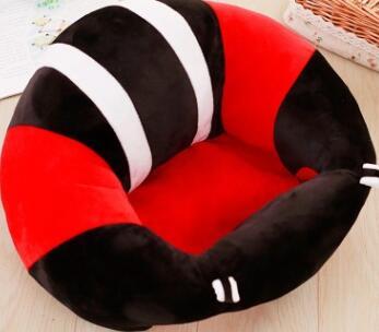 Plush toy shaped like a snake with red, black, and white colors on a wooden floor.