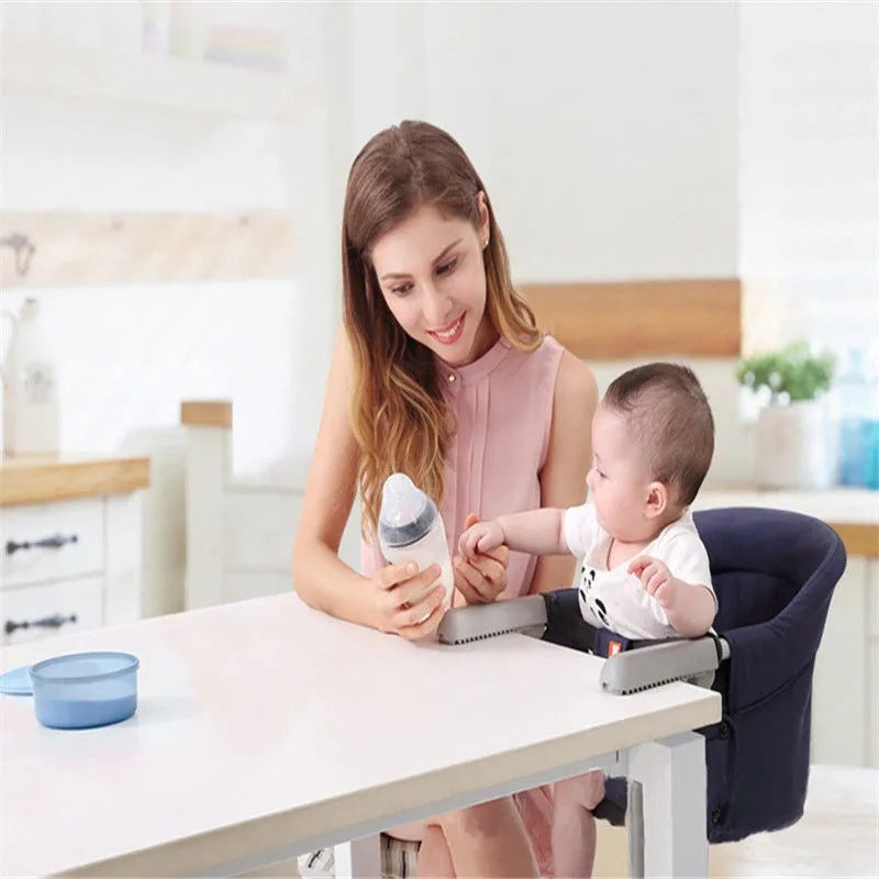 Woman with a baby in a high chair using a handheld device in a kitchen setting