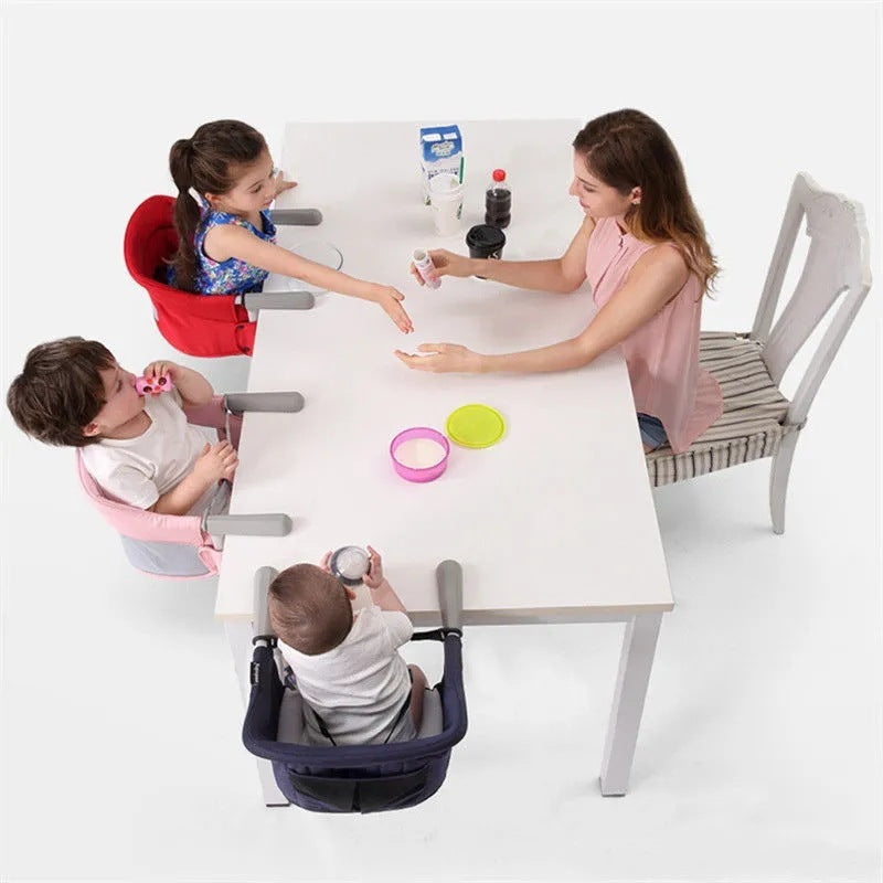 Children sitting in high chairs around a table with a woman, on a white background