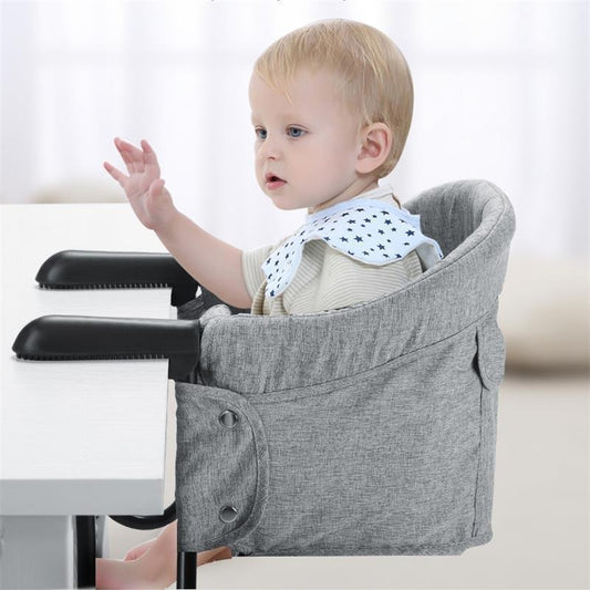 Baby in a gray high chair with a white background