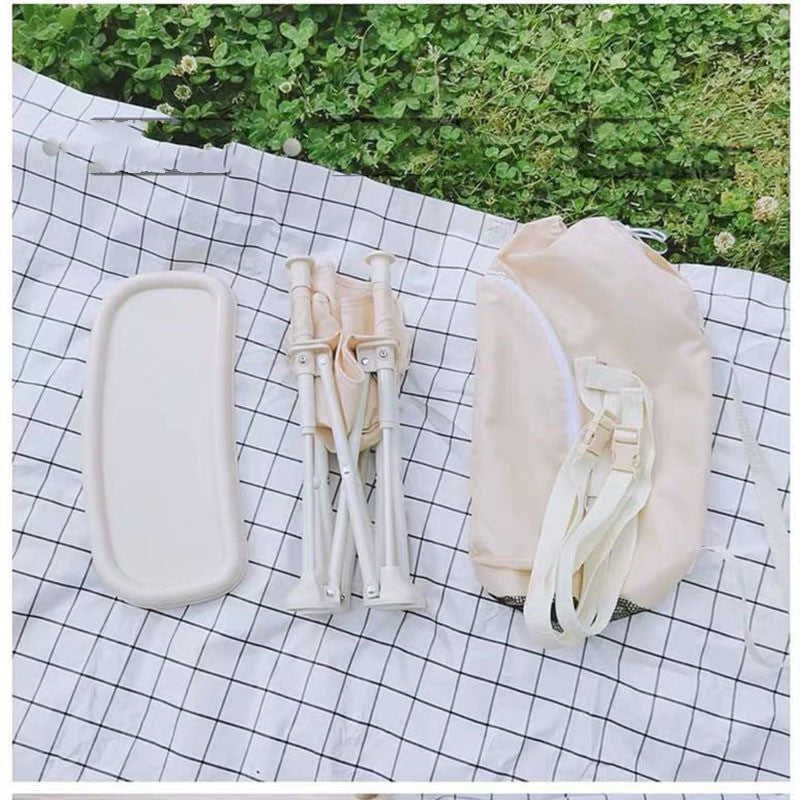 White travel accessories including a compact bag, bottle, and case on a checkered cloth with grass background.