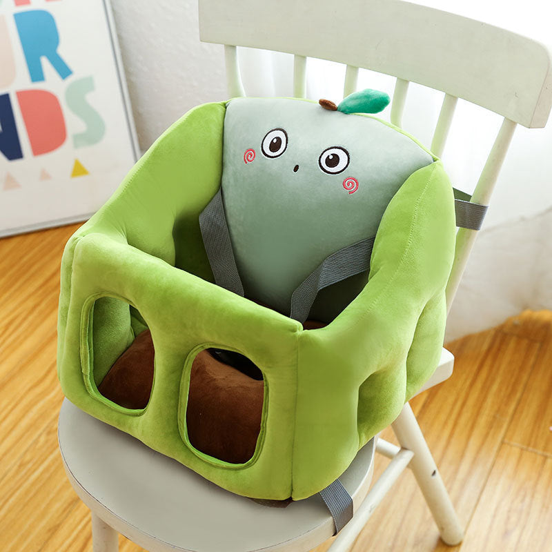 Green baby high chair with cartoon face design on a wooden floor.