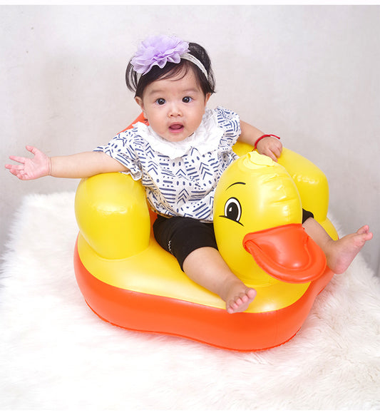 Child sitting in a yellow rubber duck-shaped inflatable seat on a white background