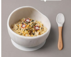 White bowl with food and a wooden spoon on a gray background