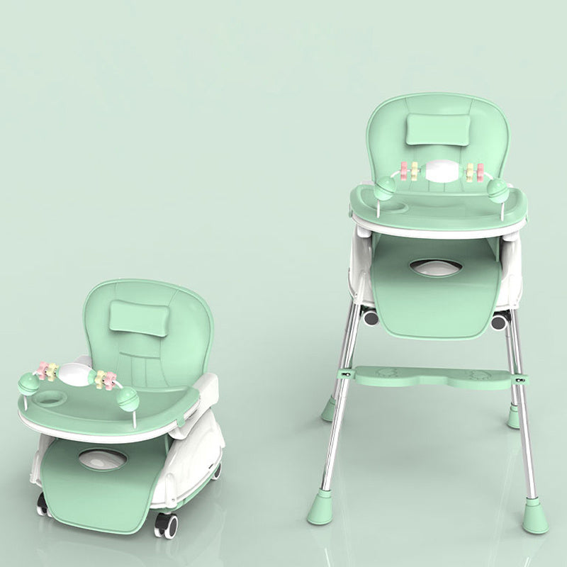 Green baby high chair with tray on a light green background