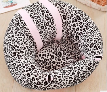 Leopard print baby seat with pink straps on a wooden floor.