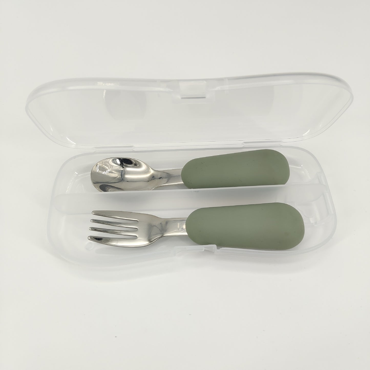Set of silver fork and spoon with green handles in a clear case on a white background