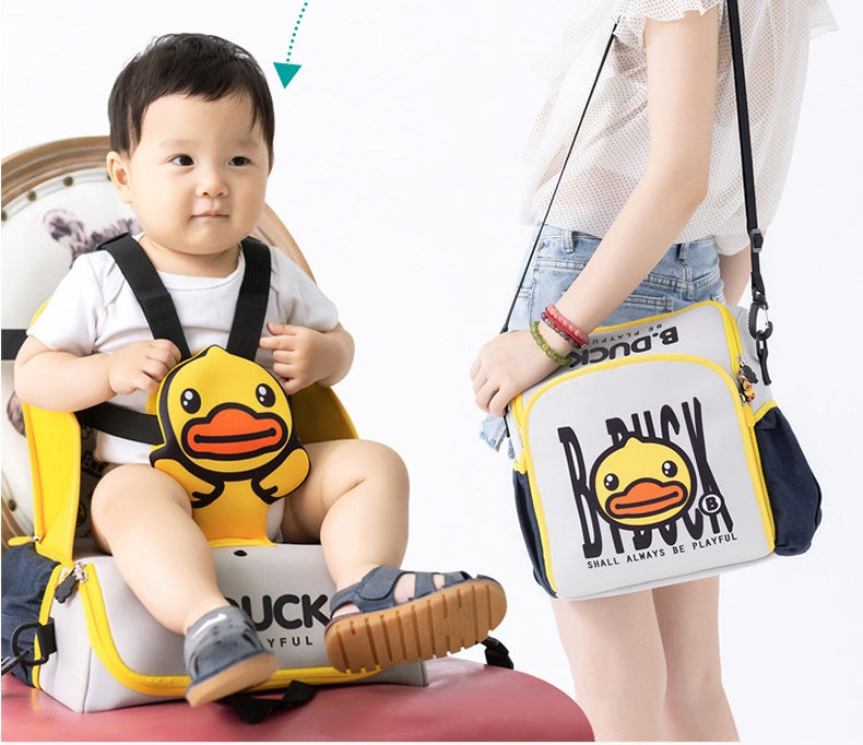 Child using a yellow and black baby seat with a matching bag, featuring a duck design.