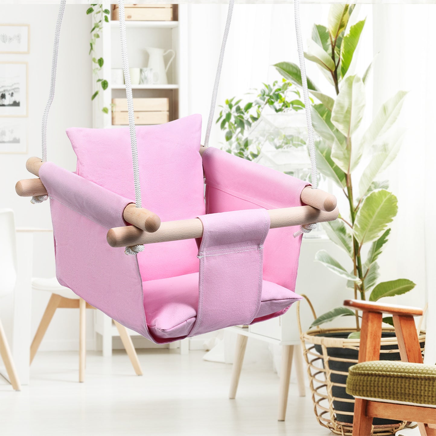 Pink children's swing chair in a room with plants and shelves.