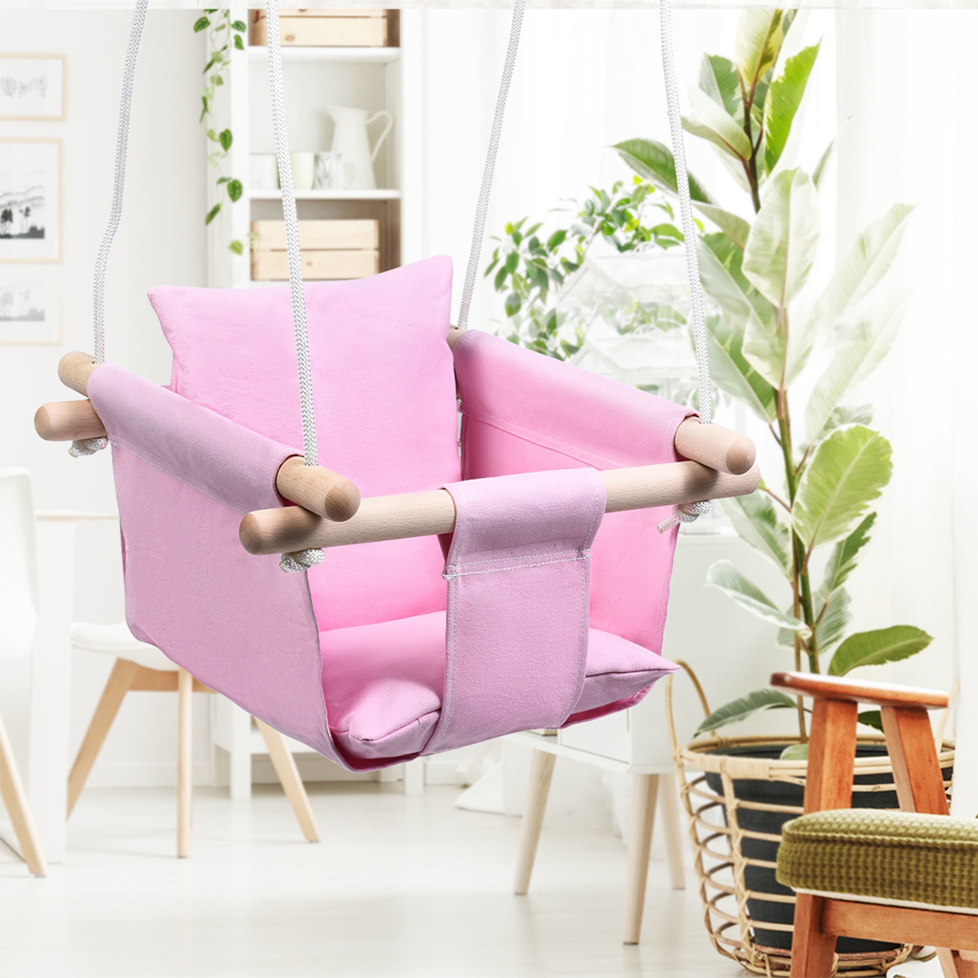 Pink children's swing chair in a room with plants and shelves.