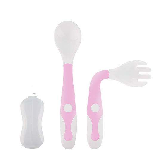 Set of pink and white baby utensils including a spoon, fork, and straw on a white background