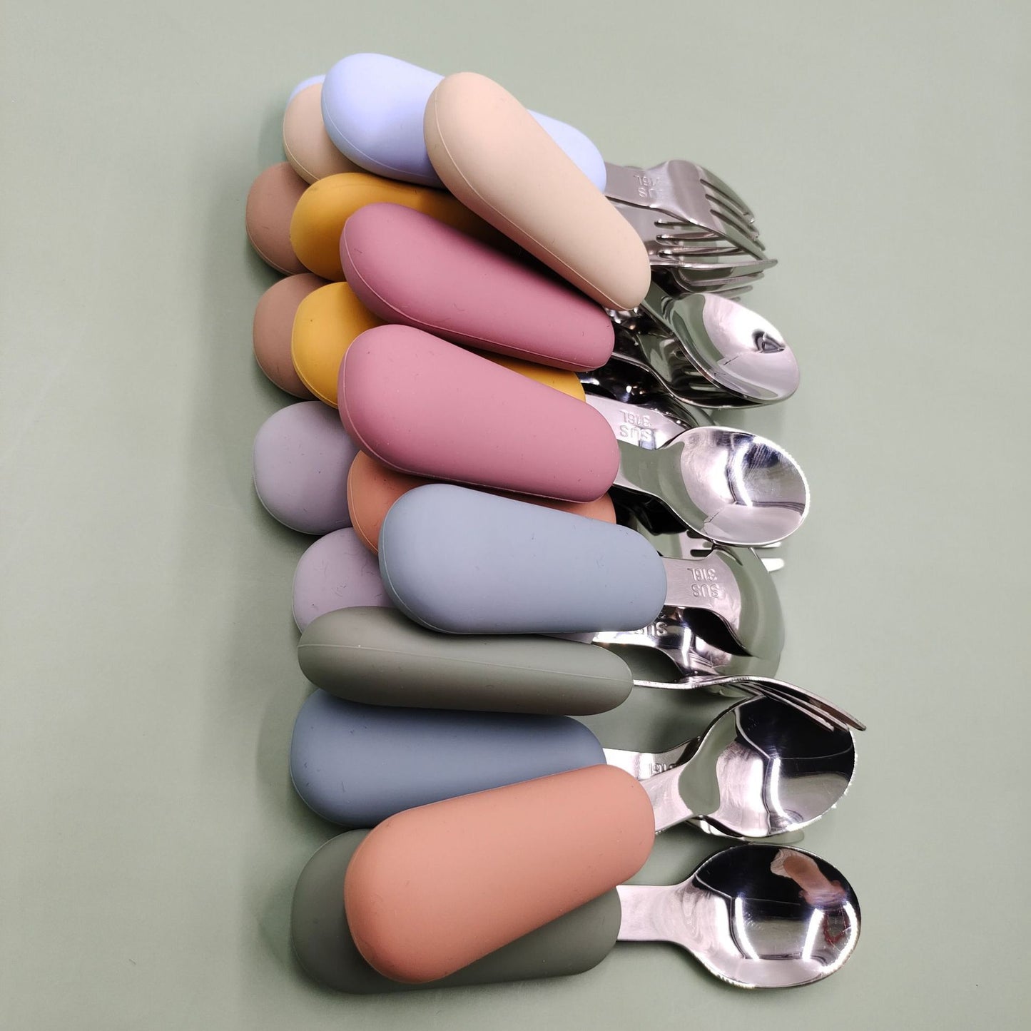 Set of spoons with colorful handles on a light green background