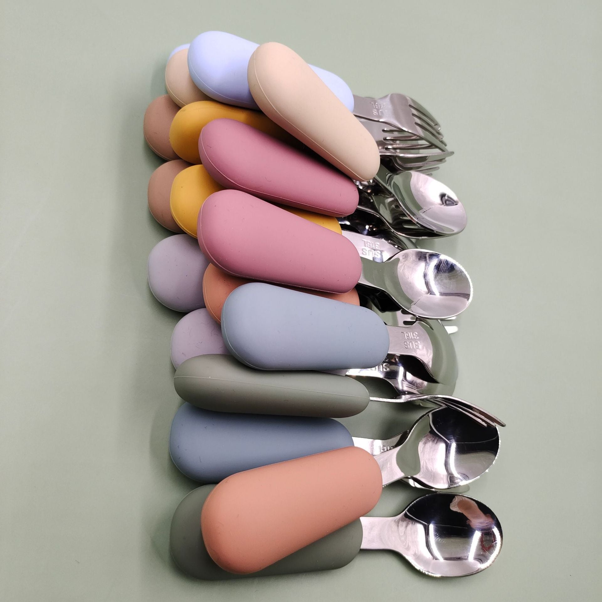 Set of spoons with colorful handles on a light green background