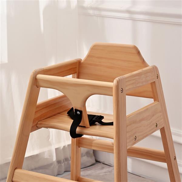 Wooden high chair with a black strap against a white curtain background