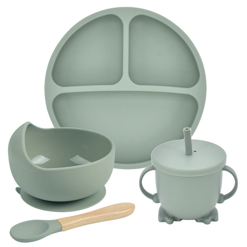 Set of green silicone dining utensils including a plate, bowl, cup with straw, and spoon on a white background.