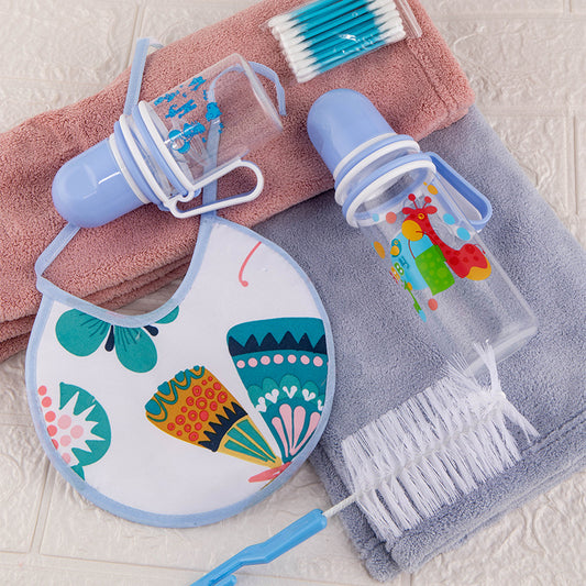 Baby bib, bottle brush, and cleaning tool on a towel with a pink towel in the background.
