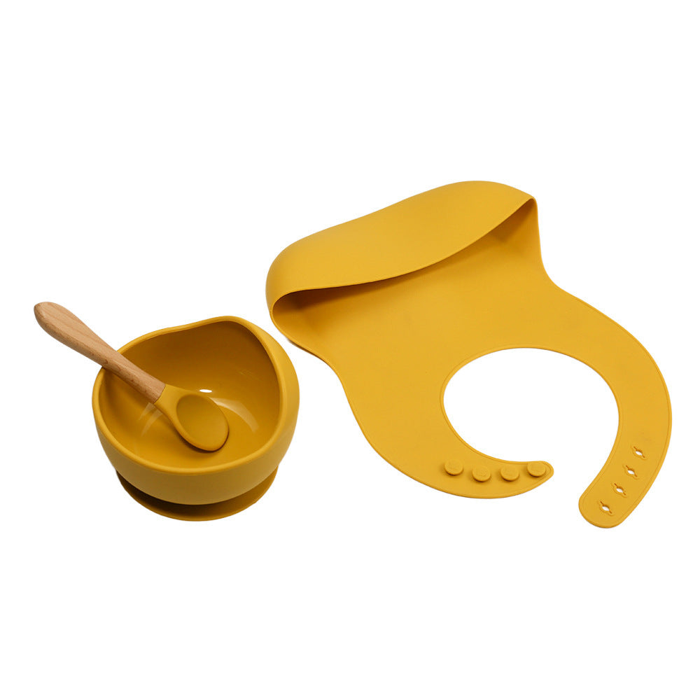 Yellow children's bowl, spoon, and bib set on a white background