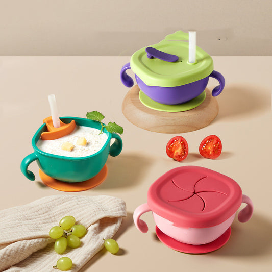 Colorful baby feeding bowls with lids and straws on a beige surface.