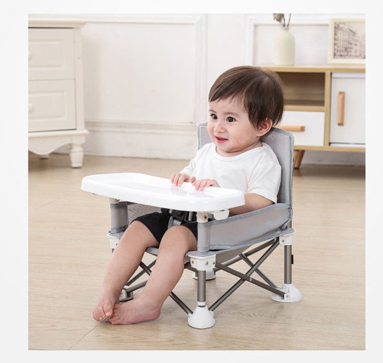 Child sitting on a portable folding chair with a tray in a home setting