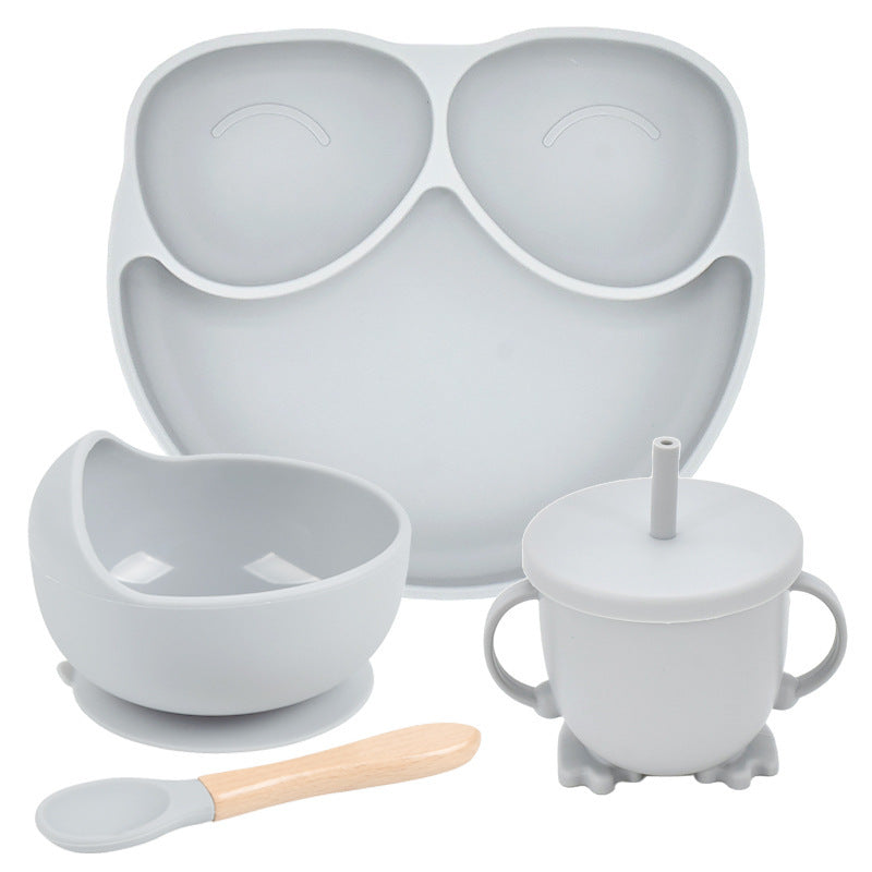 Set of gray baby feeding utensils including a tray, bowl, cup, and spoon on a white background.