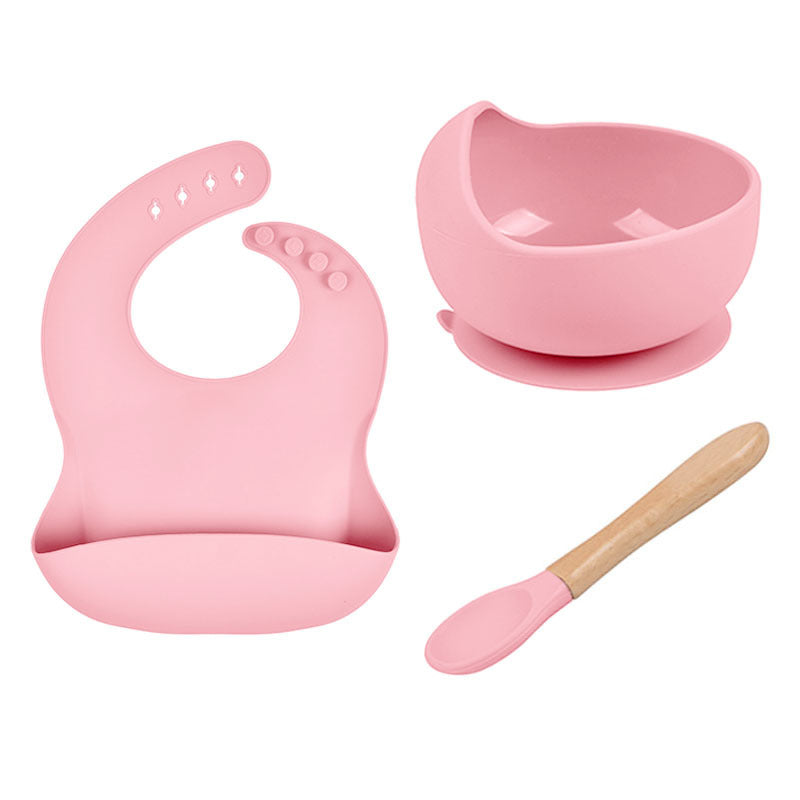 Pink baby bib, bowl, and spoon set on a white background