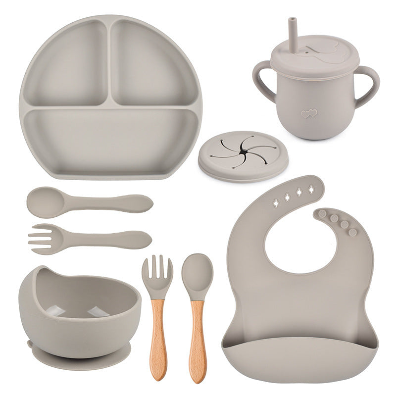 Collection of gray baby吃饭ware including a plate, cup, bowl, utensils, and bib on a white background.