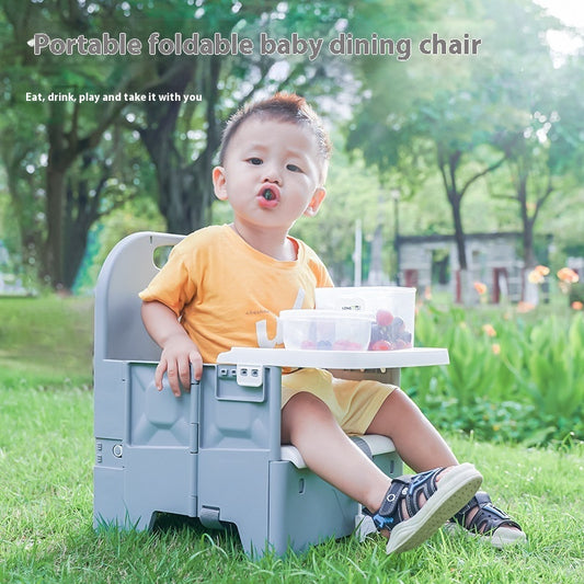 Child sitting on a portable foldable baby dining chair in a park