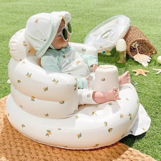 Child sitting in a white inflatable chair with floral patterns on a grassy background