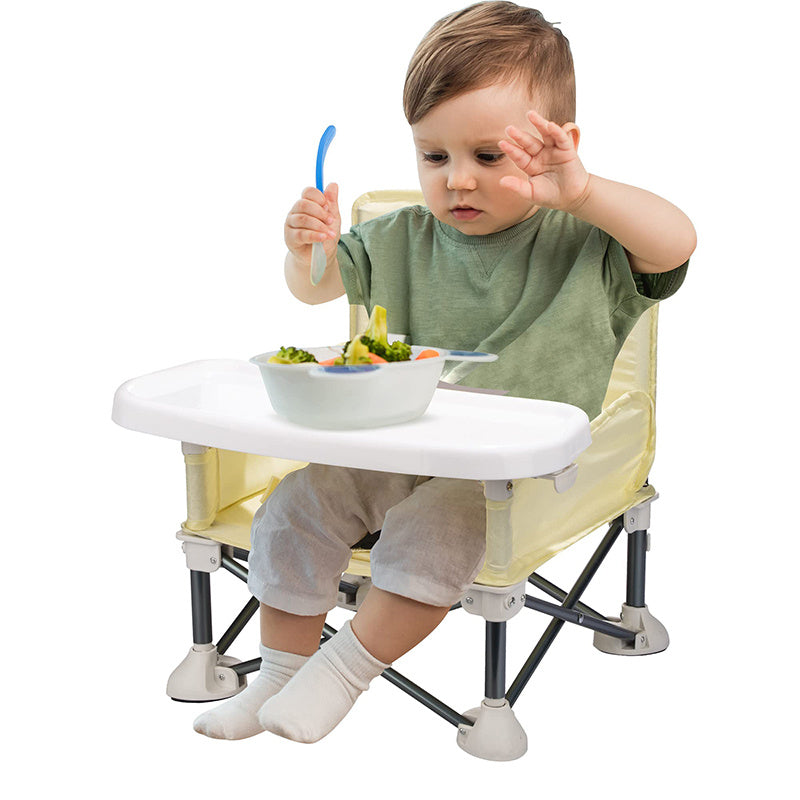 Child sitting in a yellow and white high chair with a tray, eating a meal.