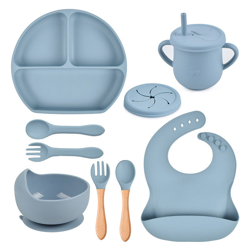Blue silicone dining set including plate, cup, bowl, utensils, and bib on a white background